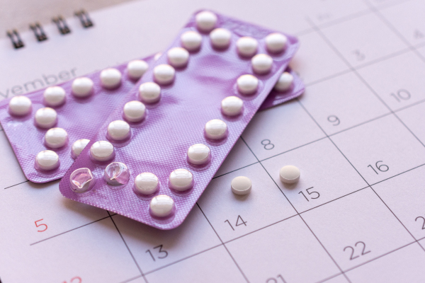 Kontracepcijske tabletke na koledarju. Boleča menstruacija.